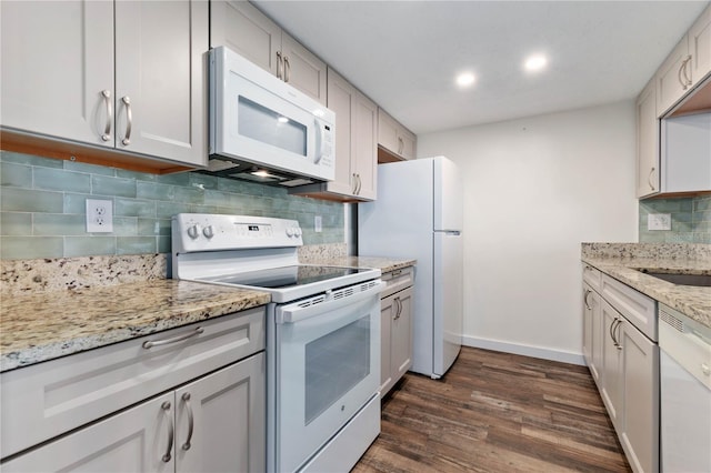 kitchen with white appliances, dark wood-type flooring, baseboards, backsplash, and light stone countertops