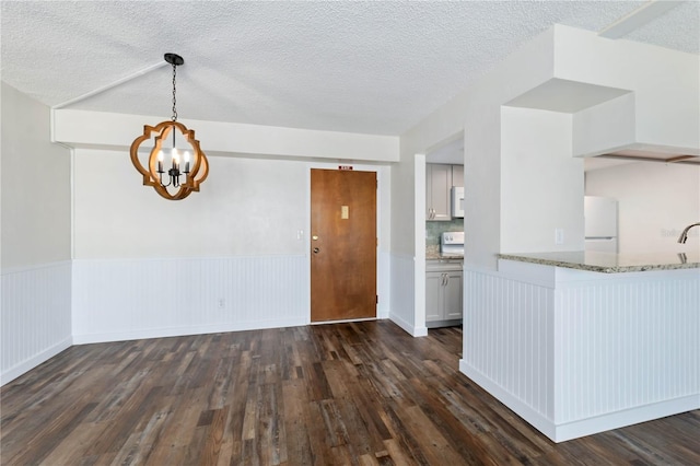 kitchen featuring wainscoting, a notable chandelier, dark wood-style flooring, and freestanding refrigerator