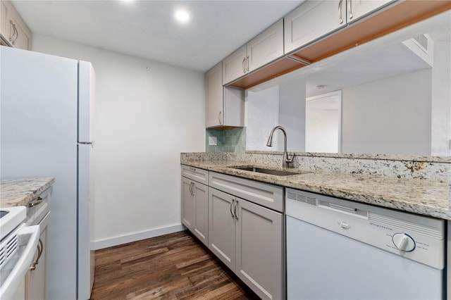 kitchen featuring decorative backsplash, dishwasher, dark wood-style flooring, light stone countertops, and a sink