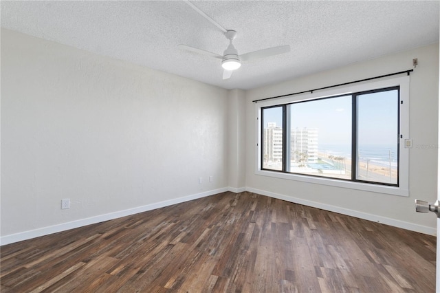 unfurnished room with dark wood-type flooring, a textured ceiling, baseboards, and a ceiling fan