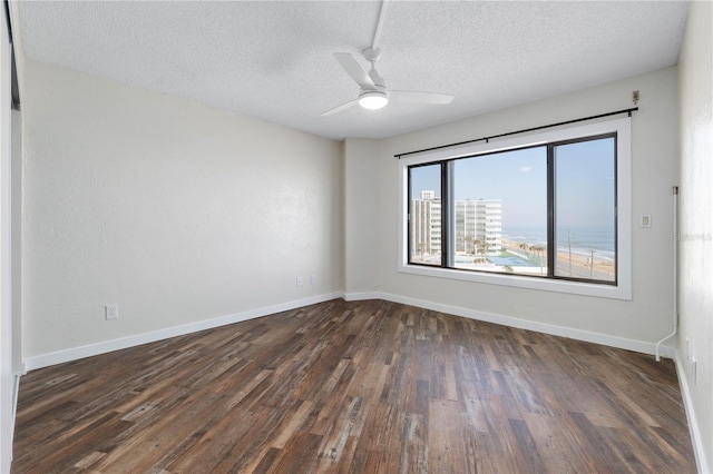 spare room featuring dark wood-style floors, a textured ceiling, a ceiling fan, and baseboards