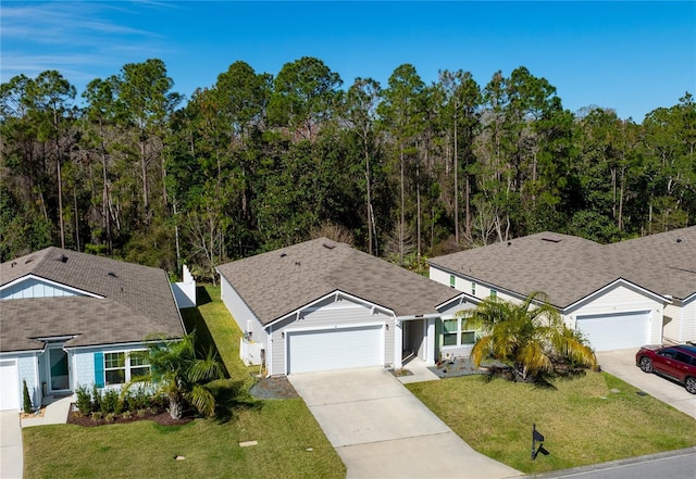 ranch-style house featuring an attached garage, a front lawn, concrete driveway, and roof with shingles