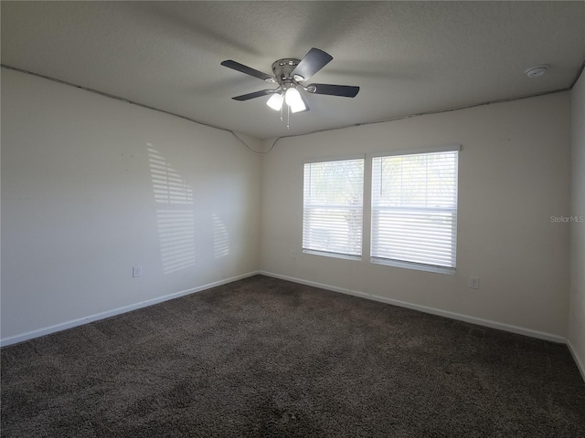 empty room with a textured ceiling, ceiling fan, dark carpet, and baseboards