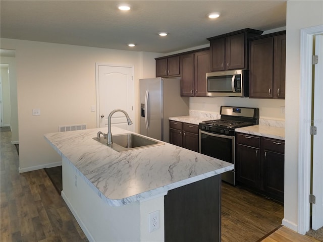 kitchen with dark wood finished floors, stainless steel appliances, recessed lighting, a sink, and an island with sink