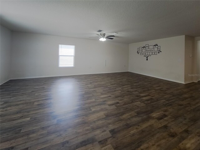 empty room featuring a ceiling fan, dark wood-style flooring, a textured ceiling, and baseboards