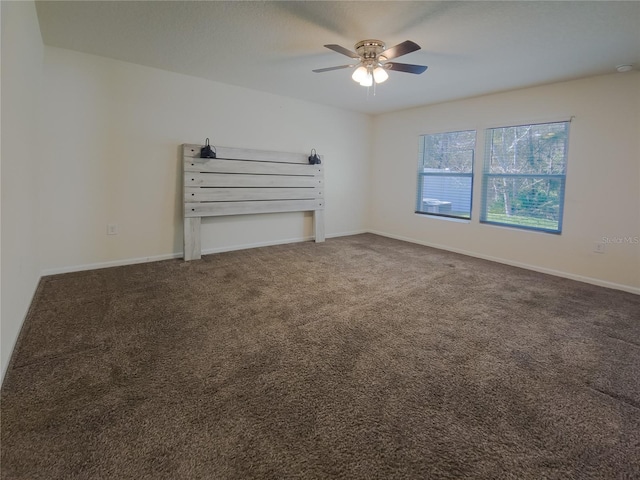 carpeted spare room with ceiling fan and baseboards