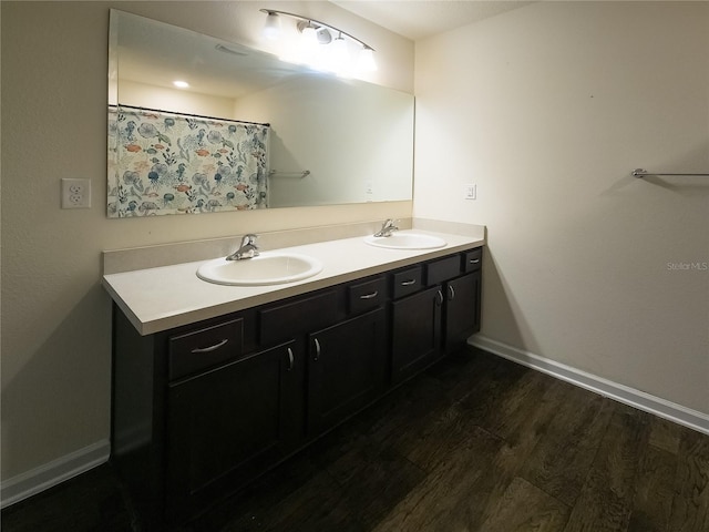 bathroom featuring double vanity, a sink, baseboards, and wood finished floors