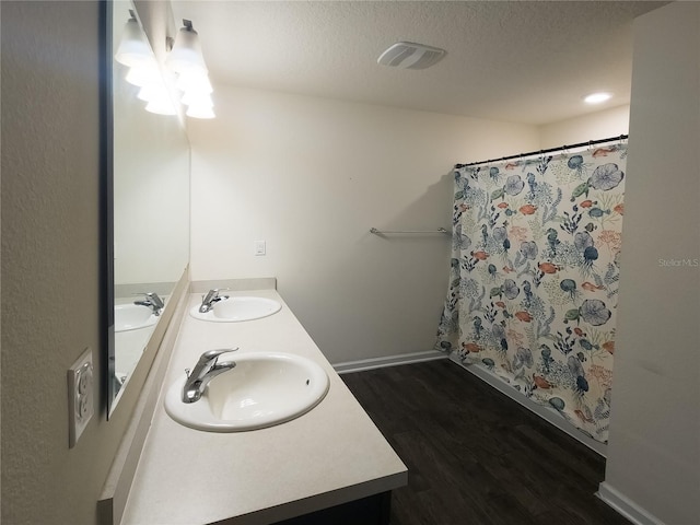 bathroom featuring a textured ceiling, wood finished floors, and a sink