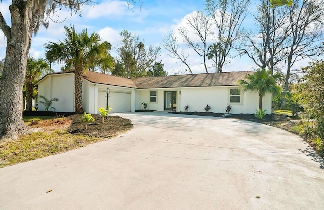 ranch-style home featuring driveway, an attached garage, and stucco siding