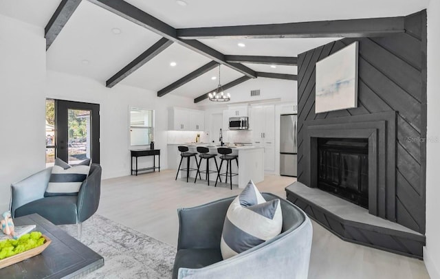 living room with lofted ceiling with beams, recessed lighting, a notable chandelier, a fireplace, and light wood-style floors