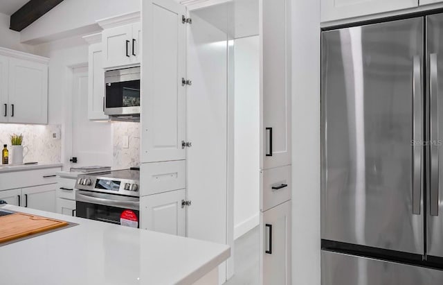 kitchen with tasteful backsplash, white cabinetry, stainless steel appliances, and light countertops