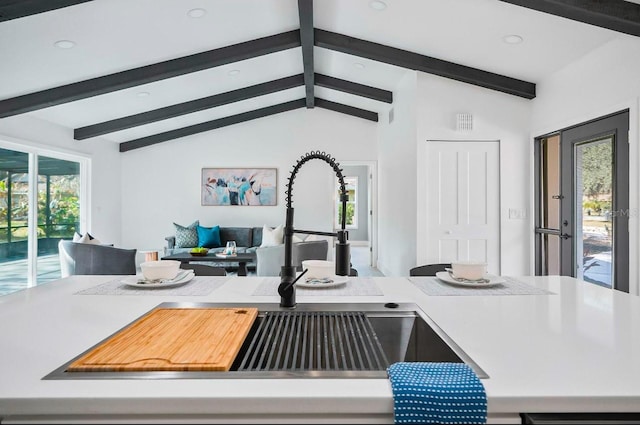 kitchen with open floor plan, light countertops, vaulted ceiling with beams, and a sink