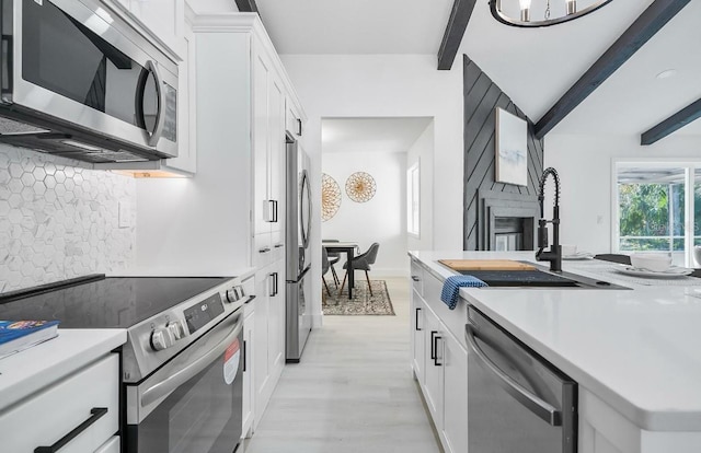 kitchen featuring stainless steel appliances, light countertops, backsplash, white cabinetry, and a sink