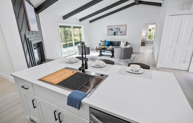 kitchen featuring lofted ceiling with beams, a fireplace, open floor plan, and light countertops