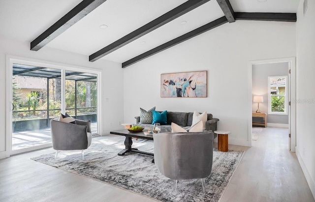 living area with lofted ceiling with beams, baseboards, and wood finished floors