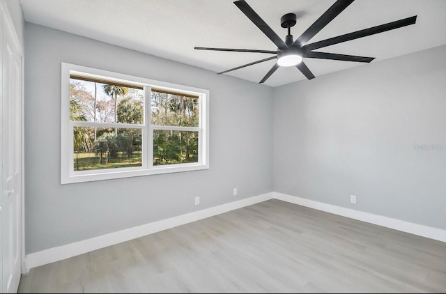 unfurnished room with ceiling fan, wood finished floors, and baseboards