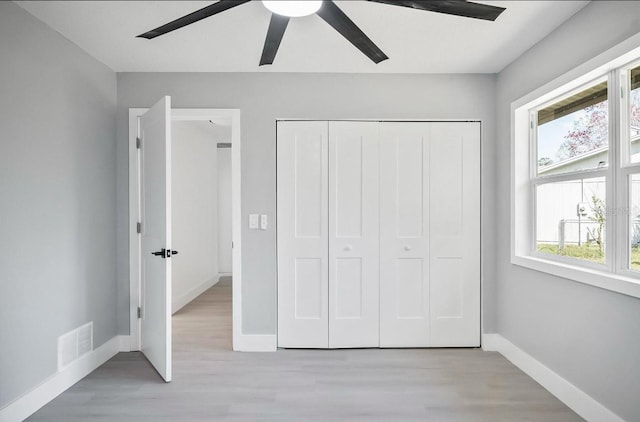 unfurnished bedroom featuring ceiling fan, visible vents, baseboards, a closet, and light wood finished floors