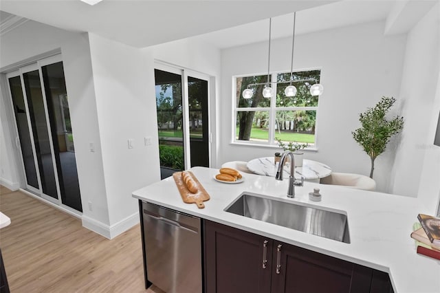 kitchen with light wood-style flooring, a sink, light countertops, hanging light fixtures, and dishwasher