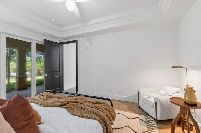 bedroom featuring ornamental molding, wood finished floors, a raised ceiling, and baseboards