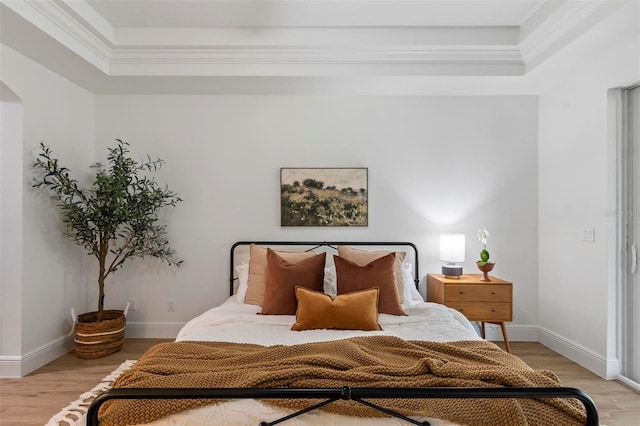 bedroom with arched walkways, light wood-style flooring, and baseboards