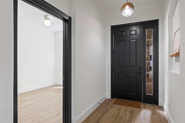 entryway featuring ornamental molding, wood finished floors, and baseboards