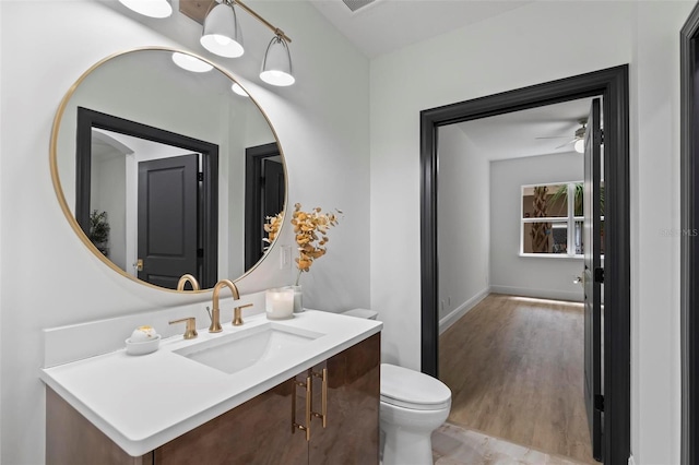 bathroom with toilet, baseboards, wood finished floors, and vanity