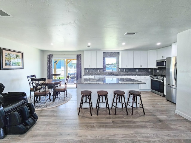 364 Palm Cir, Flagler Beach, FL 32136 - kitchen featuring appliances with stainless steel finishes, a kitchen island, light wood-type flooring, and a kitchen bar