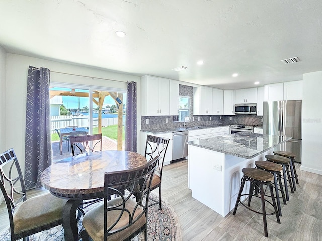 364 Palm Cir, Flagler Beach, FL 32136 - kitchen with light wood-style flooring, stainless steel appliances, a kitchen island, a sink, and visible vents