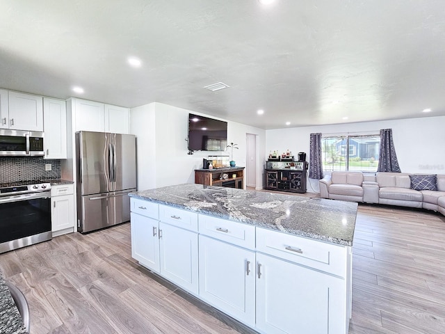 364 Palm Cir, Flagler Beach, FL 32136 - kitchen with appliances with stainless steel finishes, white cabinetry, light wood-style floors, and dark stone countertops