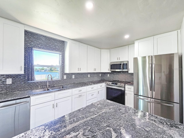 364 Palm Cir, Flagler Beach, FL 32136 - kitchen with tasteful backsplash, appliances with stainless steel finishes, white cabinets, a sink, and dark stone countertops