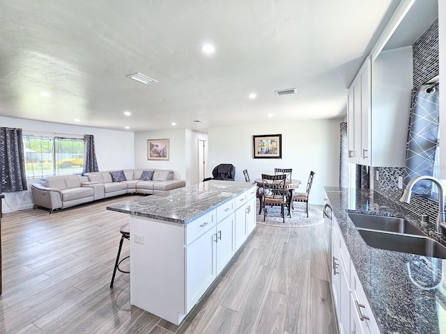 364 Palm Cir, Flagler Beach, FL 32136 - kitchen featuring light wood-style flooring, a breakfast bar, a kitchen island, a sink, and visible vents