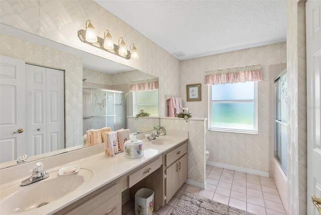 33 Poinsettia Ln, Palm Coast, FL 32164 - bathroom featuring double vanity, tile patterned flooring, a textured ceiling, combined bath / shower with glass door, and wallpapered walls