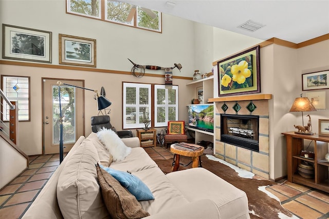 living room with a towering ceiling, stairs, a fireplace, and visible vents