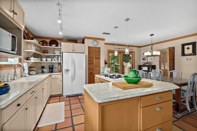 kitchen with a kitchen island, a sink, visible vents, light countertops, and white fridge with ice dispenser