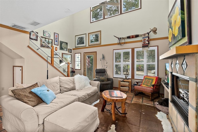 living room with a high end fireplace, visible vents, stairway, and a high ceiling