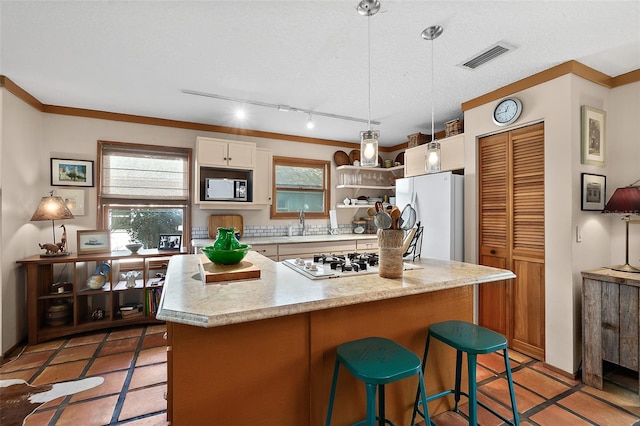 kitchen featuring white appliances, white cabinetry, visible vents, and a breakfast bar area