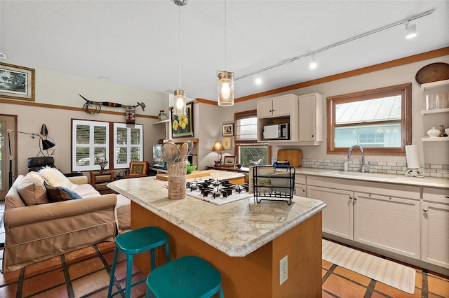 kitchen featuring a breakfast bar area, stainless steel microwave, open floor plan, a kitchen island, and a sink