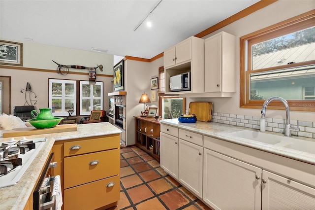 kitchen featuring white stovetop, light countertops, a glass covered fireplace, open floor plan, and a sink