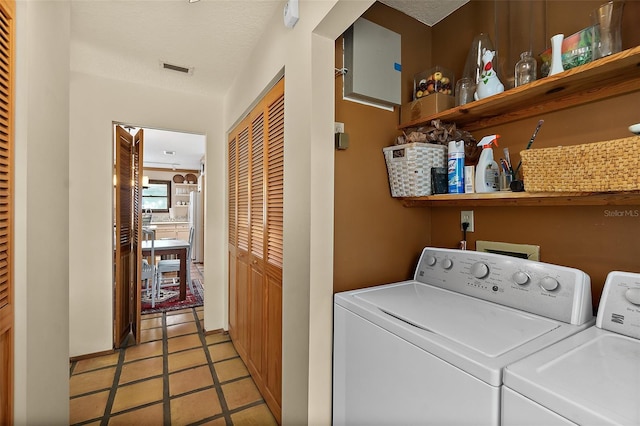 clothes washing area with light tile patterned floors, a textured ceiling, laundry area, visible vents, and washer and clothes dryer