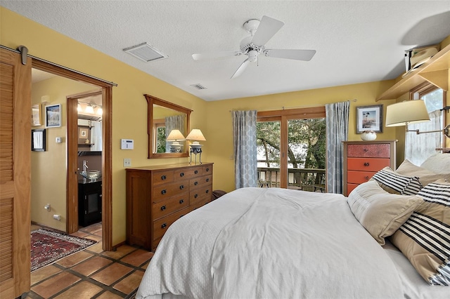 bedroom with access to exterior, visible vents, a barn door, a sink, and a textured ceiling