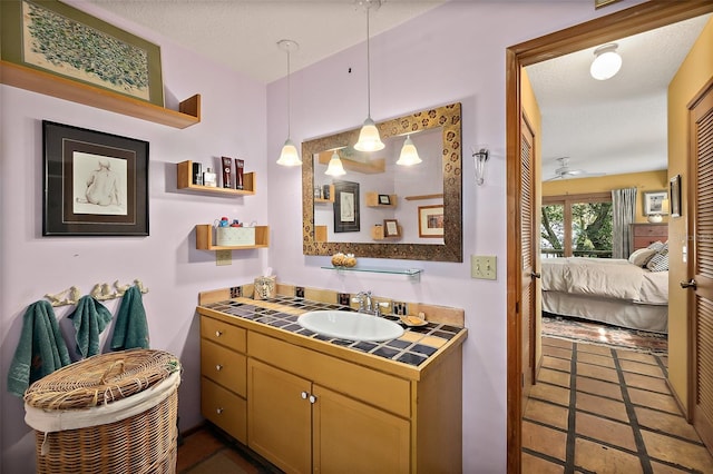 bathroom featuring ceiling fan, vanity, ensuite bath, a textured ceiling, and tile patterned floors