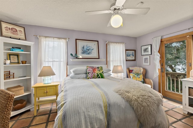 bedroom featuring access to outside, a textured ceiling, and a ceiling fan