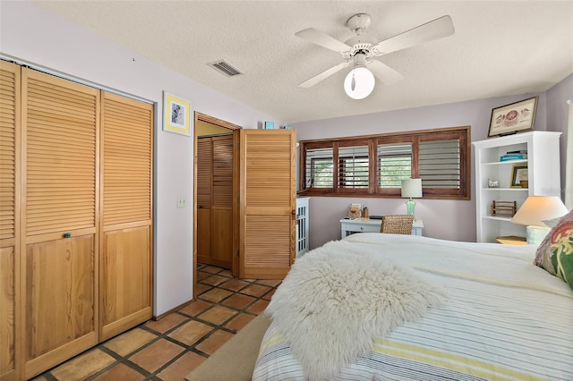 bedroom featuring ceiling fan, visible vents, a textured ceiling, and light tile patterned flooring