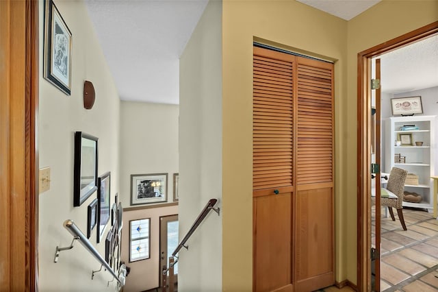 hallway with a textured ceiling and an upstairs landing