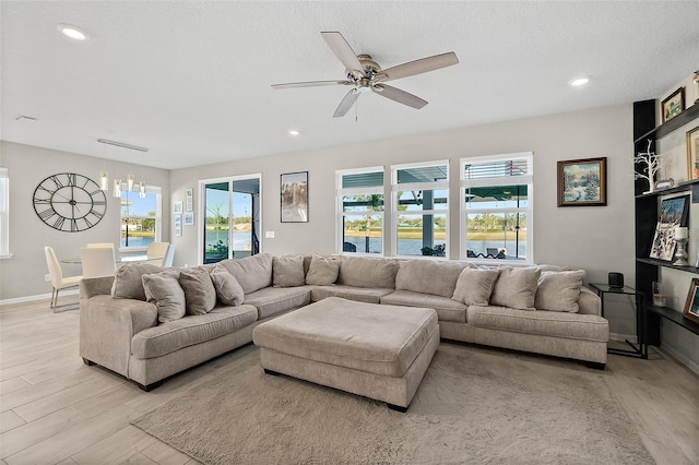 living room with baseboards, ceiling fan with notable chandelier, light wood-type flooring, and recessed lighting