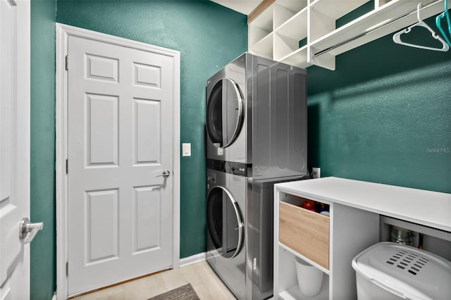 clothes washing area featuring laundry area, stacked washer and clothes dryer, and a textured wall