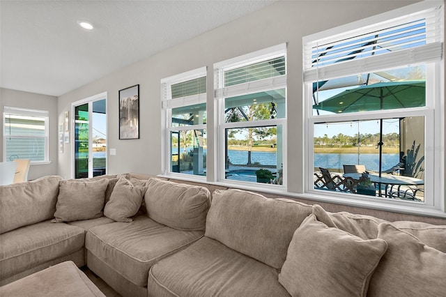 living room with plenty of natural light, a water view, and recessed lighting