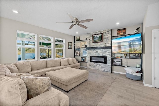 living area with recessed lighting, ceiling fan, baseboards, and a stone fireplace