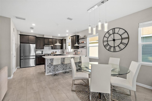 dining space featuring visible vents, light wood-style flooring, and baseboards