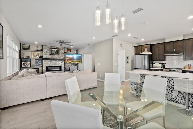 dining room with baseboards, visible vents, a ceiling fan, a stone fireplace, and recessed lighting